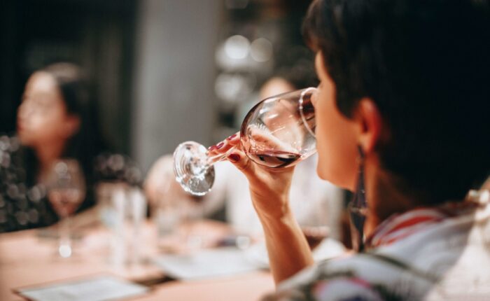 Mujer catando un vino tinto en una mesa con más personas